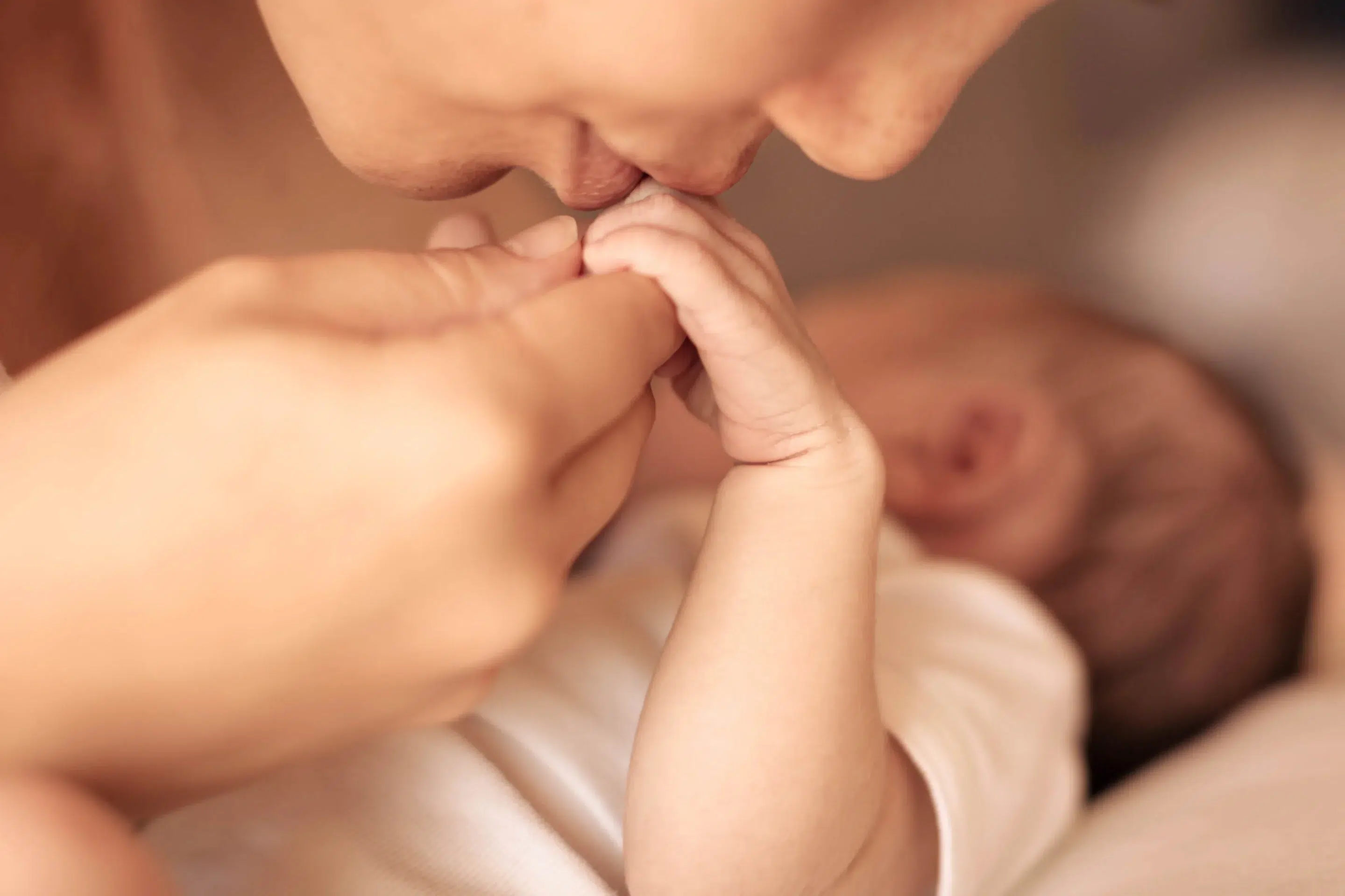 A mother kissing and holding hand the hand of her newborn baby A mother kissing and holding hand the hand of her newborn baby